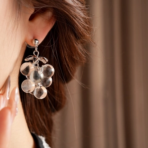 Macro shot of silver crystal grape tassel earrings on model with soft lighting