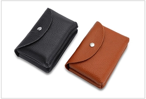 Detail of mini leather coin purses in black and brown with litchi texture and metal snaps