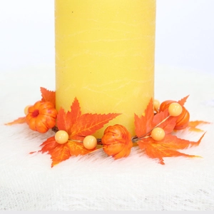 Autumn candle ring with maple leaves and small pumpkins on a white textured surface