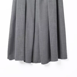 Detailed macro view of the grey accordion pleats and fine fabric texture on the skirt hem