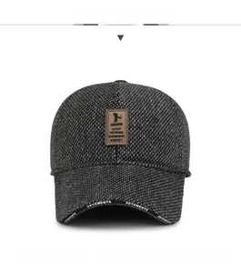Detail of dark grey tweed baseball cap with leather patch and branded brim edge