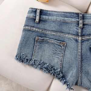 Detailansicht der Gesäßtaschen und des ausgefransten Saums der blauen Denim-Shorts