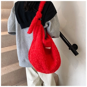 Close-up of red plush fuzzy bag showing knotted shoulder strap and soft fur texture