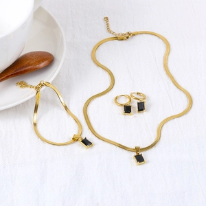 Conjunto de joyas doradas con cristales negros cuadrados sobre tela blanca elegante
