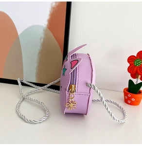Close-up of purple unicorn crossbody bag with golden flower zipper and woven silver strap
