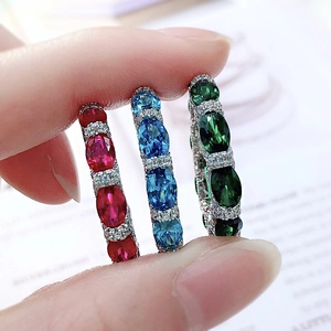 Close-up of three sterling silver rings with red, blue, and green oval gemstones