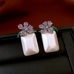 Elegante lila Diamant-Blumenohrringe mit weißem Perlenanhänger auf schwarzer Box