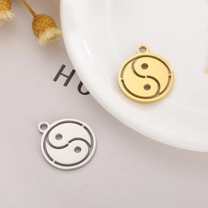 Detailed view of hollow Tai Chi Yin Yang charms in gold and silver stainless steel