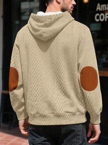 Détail du sweat à capuche jacquard abricot avec motifs de losanges et coudières marron