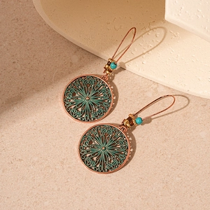 Close-up of vintage bronze flower earrings with turquoise beads and oxidized finish detail