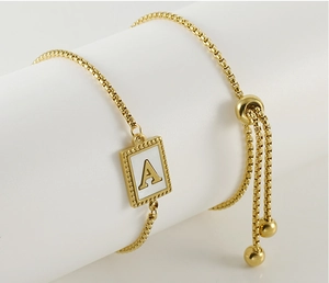 Macro detail of golden box chain bracelet with adjustable slider and letter A pendant