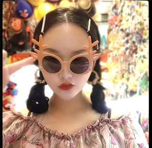 Close-up of reindeer antler Christmas party glasses worn by a model in a festive style