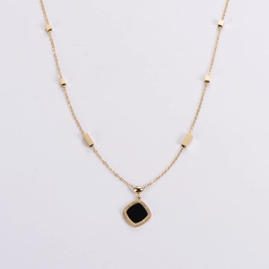 Macro detail of gold necklace with Roman numerals pendant and cubic charms on chain