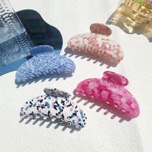 Set of four large acetate hair claws featuring marble and floral patterns on white background