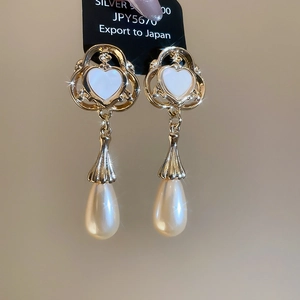 Close-up of vintage S925 silver earrings with heart shell inlay and teardrop pearls