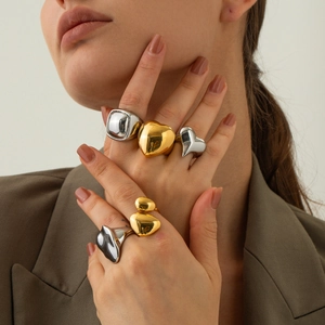 Exaggerated 18K gold and silver spherical heart rings shown on a model hand