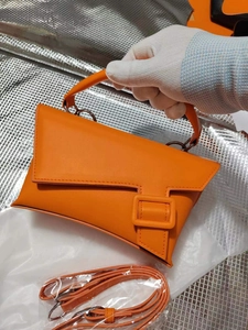 Detail of orange hourglass leather handbag with adjustable strap and buckle closure