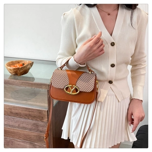 Close-up of brown patchwork handbag featuring herringbone fabric and golden V-shaped buckle