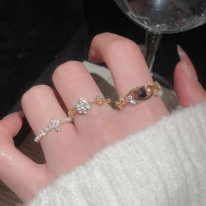Detailed shot of three gold rings with pearls, stars, and crystals on a model's hand