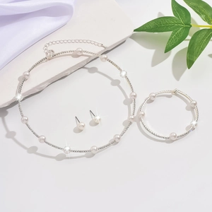 Flat lay of single-row pearl and rhinestone bridal jewelry set with necklace and earrings