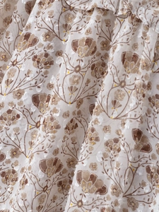 Gros plan sur tissu mousseline blanc avec motifs floraux marrons et volants