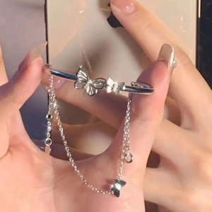 Detail of silver butterfly cuff bracelet with delicate tassel chains on female model wrist