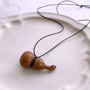 Gros plan du pendentif gourde en bois sur une assiette en céramique crème avec cordon