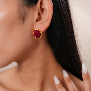Close-up of vintage round geometric stud earrings with gold frames and deep red velvet inlay