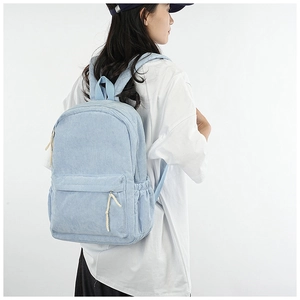 Detail of light blue corduroy backpack texture with a zip pocket and woven zipper pull