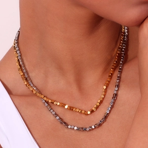 Minimalist 3mm gold and silver beaded cube necklaces layered on a female neck