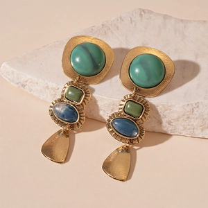 Détail de boucles d'oreilles vintage avec pierres en résine verte et bleue sur base pierre