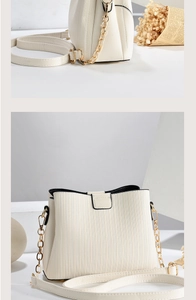 Detailed close-up of ivory crossbody bag with vertical textures and gold chain strap