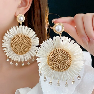 Detail of woven sunflower earrings with pearls and crystal pendants on a model