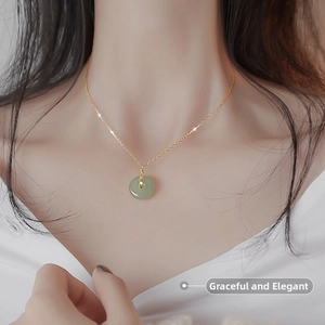 Close-up of elegant green jade Ping'an Kou pendant on a thin gold stainless steel chain