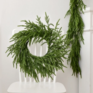 Realistic Norfolk pine Christmas wreath in deep green PE hanging on a white chair