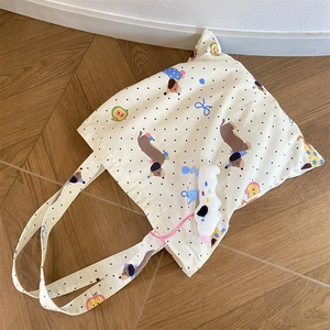 Dachshund print canvas tote bag with polka dots and soft white plush charm on wood floor