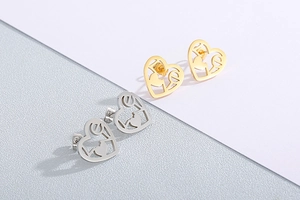 Macro shot of gold and silver heart-shaped stud earrings with LOVE hollow engraving