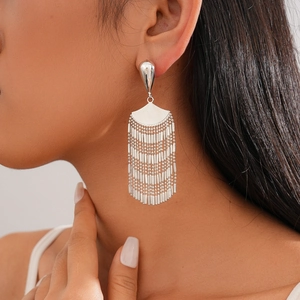Macro shot of silver fan-shaped fringe earrings on model showcasing metallic flow and shine
