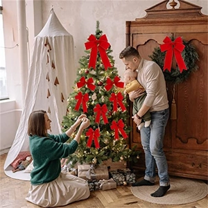 Family decorating Christmas tree with large red velvet bows with gold wired edges