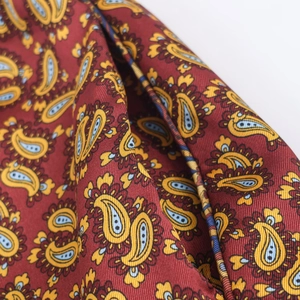 Close-up of deep red paisley pattern fabric showing intricate print detail and fine stitching