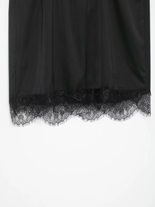 Vue macro du tissu satiné noir avec bordure en dentelle délicate sur le bas du haut