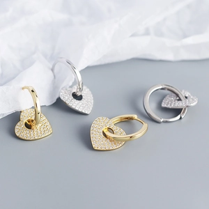 Macro shot of silver and gold heart hoop earrings with pavé crystal accents