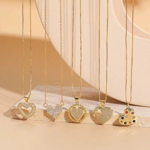 Five gold plated heart necklaces with sparkling zircons on elegant beige stone slabs