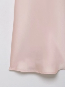Gros plan de l'ourlet de la robe en satin rose avec coutures fines et tissu soyeux