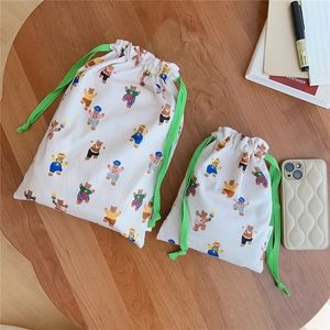 Detail of two drawstring cotton bags with cartoon bear prints on a wooden desk setup