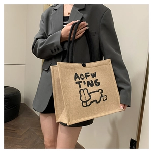 Linen tote bag with black rope handles and rabbit print shown in a lifestyle setting