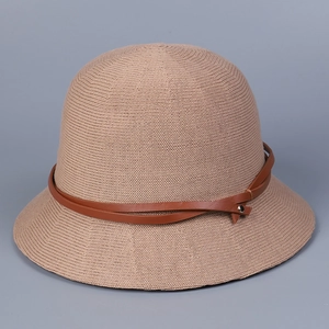 Close-up of khaki knitted bucket hat featuring brown leather strap and metal rivet detail