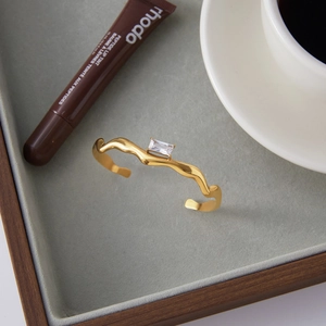 Gold-plated wavy open cuff bracelet with a rectangular white zircon in a tray