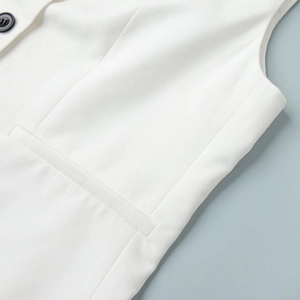 Detail of white V-neck vest featuring fine woven texture and premium black button