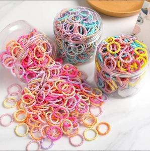 Colorful high-elastic hair ties for kids in transparent jars on marble surface